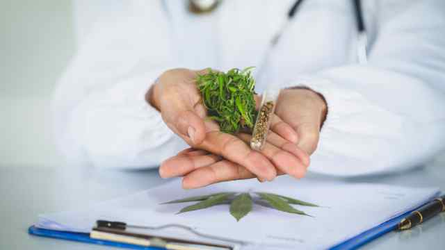 person in a white lab coat holding medical cannabis